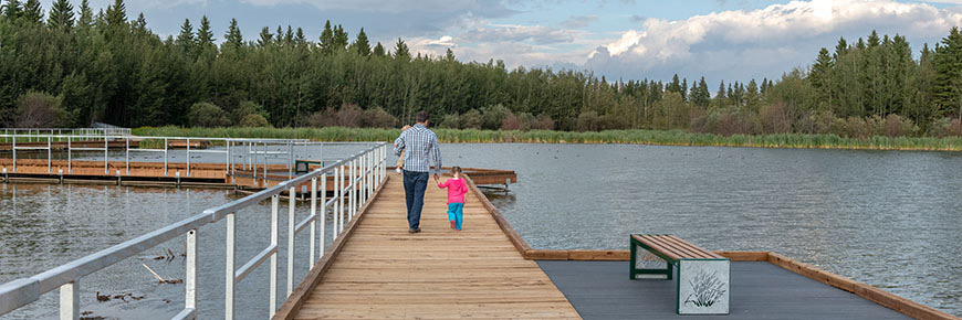 A father and daughter walk past various waterfowl species on the Living Waters Boardwalk.