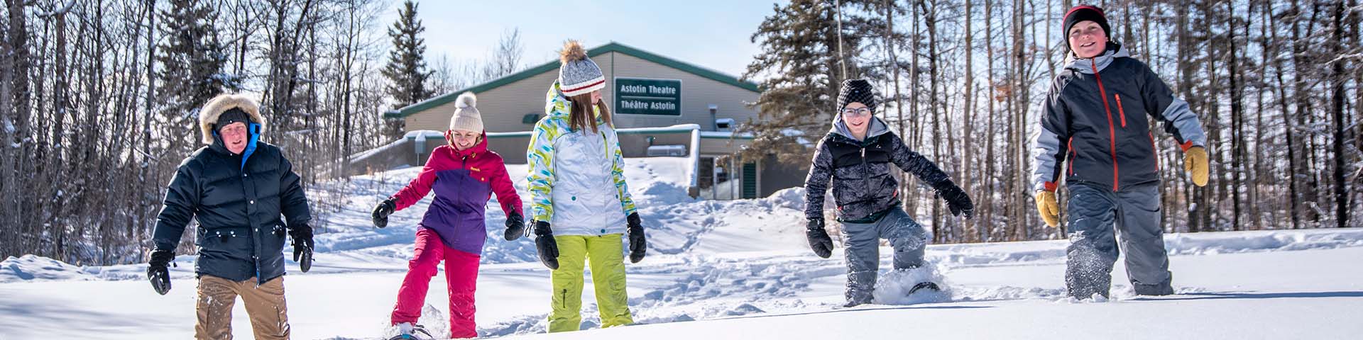 Une famille chaussée de raquettes s’amuse dans la neige à l’aire récréative du lac Astotin, dans le parc national Elk Island. 