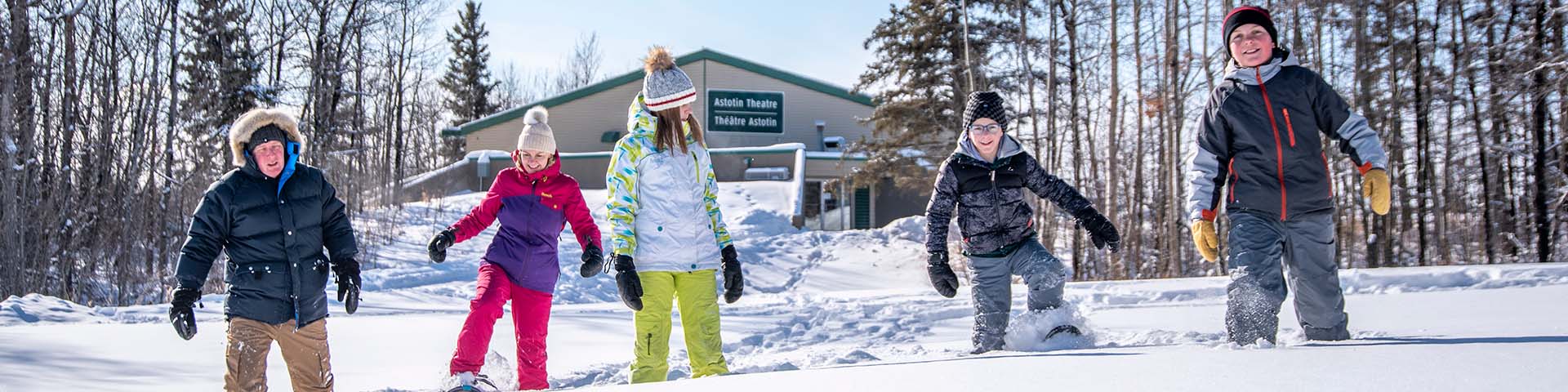 A family on snowshoes playing in the snow at the Astotin Lake Recreation Area in Elk Island National Park.