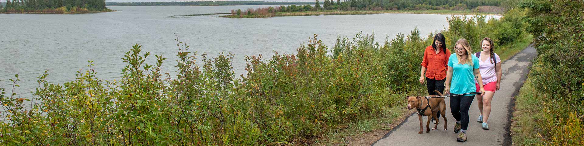 Elk Island Hikers walk a dog along the shores of Astotin Lake... Elk Island National Park