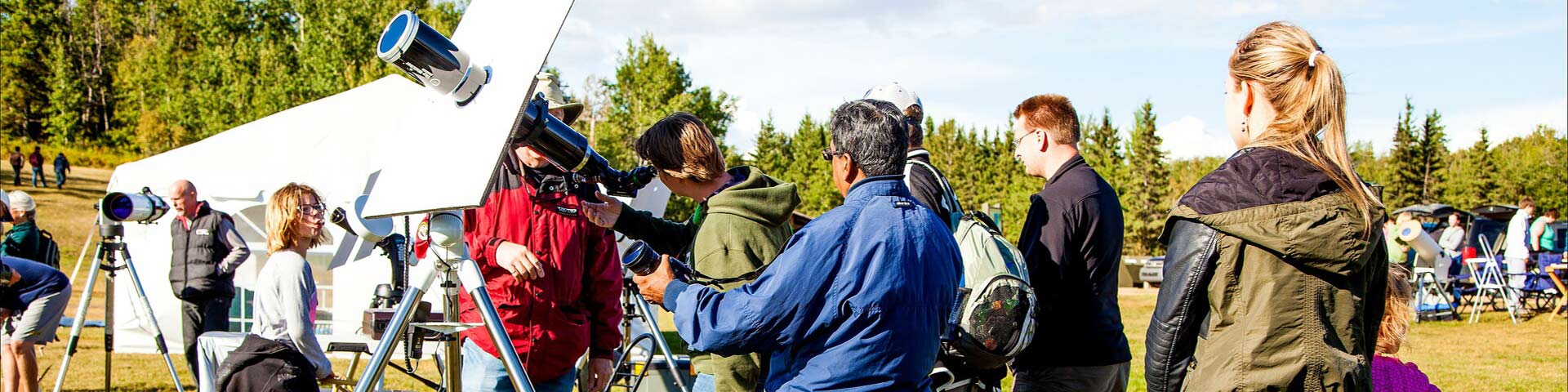 Un membre de la Société Royale d’Astronomie du Canada (Edmonton) à côté d’un télescope discute l’observation du soleil avec les visiteurs dans le parc national Elk Island.