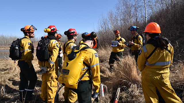 A group of Parks Canada wildland firefighters listens to a safety briefing