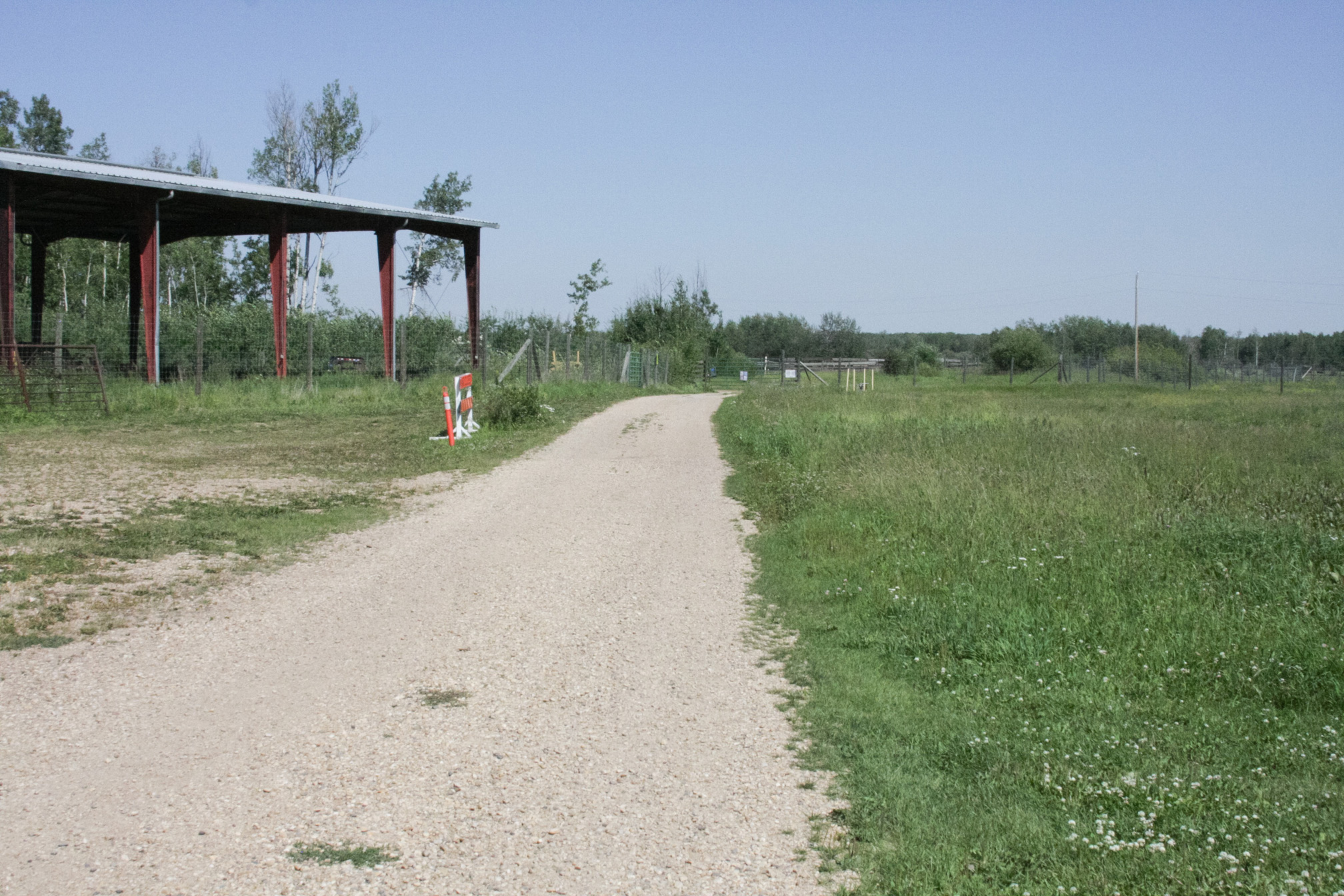 Un chemin de service en gravier avec une prairie herbeuse d’un côté.