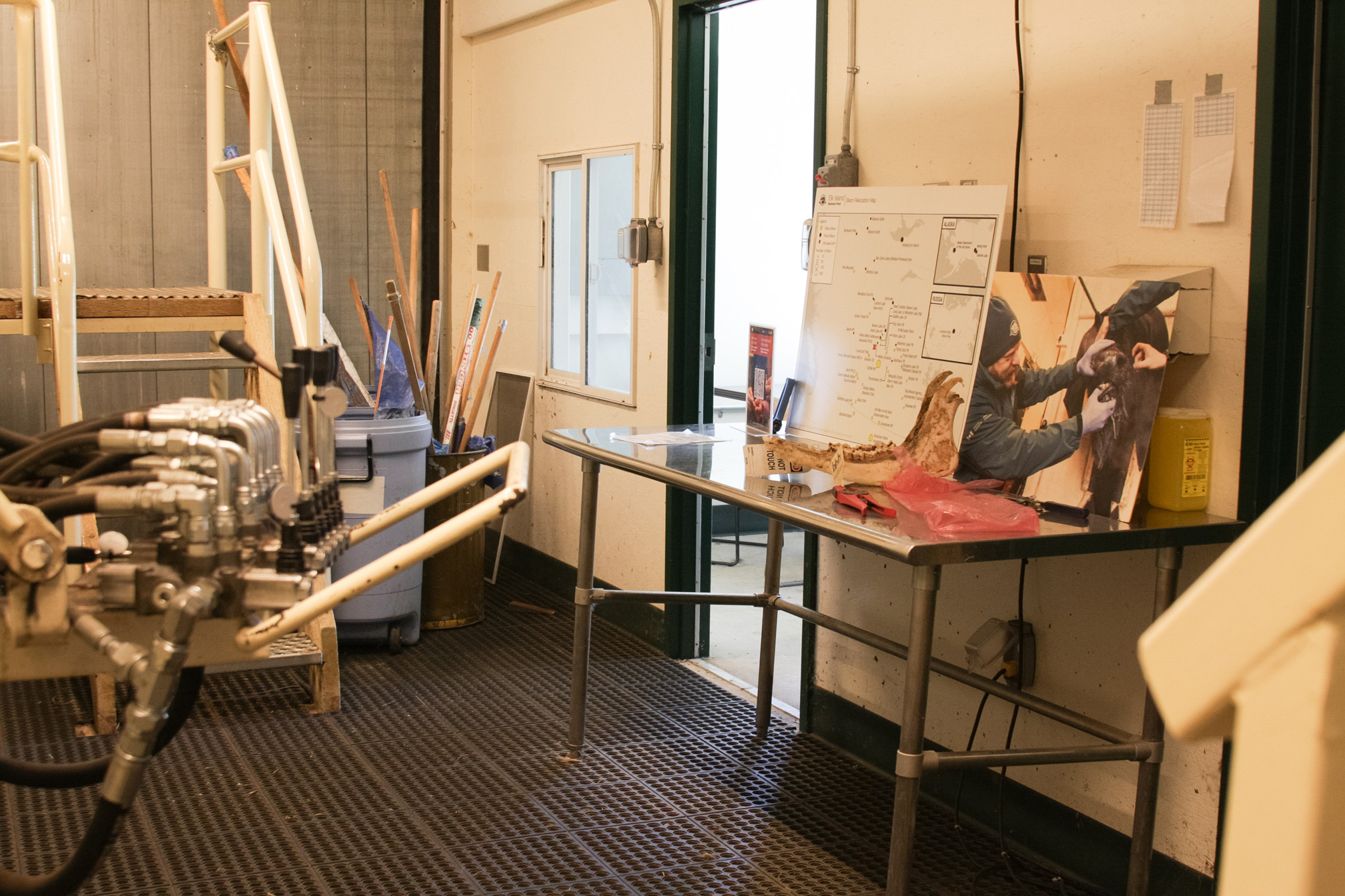Une petite pièce présente un aménagement avec une table en métal, des accessoires et des mécanismes de contrôle hydraulique.
