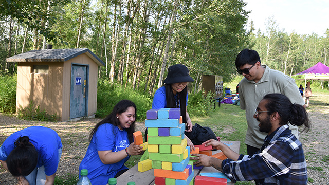 A group of people playing giant Jenga at a campsite in Elk Island National Park