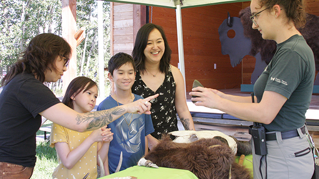 A family looks at an interpreter holding an artifact.