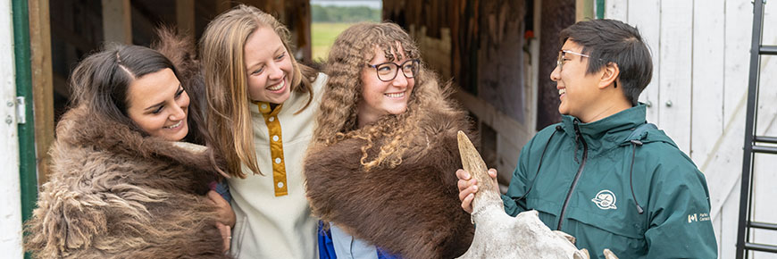 Three visitors listen to a park interpreter share the cultural significance of bison hides to Indigenous peoples.