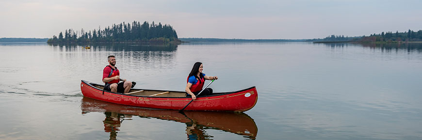 A couple paddles their canoe across Astotin Lake.