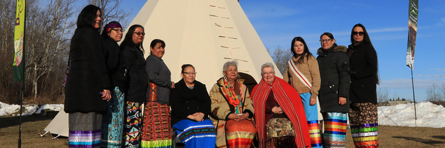 Des femmes des traités no 6 et no 7 et de la Nation métisse de l'Alberta posent pour une photo devant un tipi après la cérémonie d'adieu des bisons envoyés du parc national Elk Island au parc national Banff en 2017..