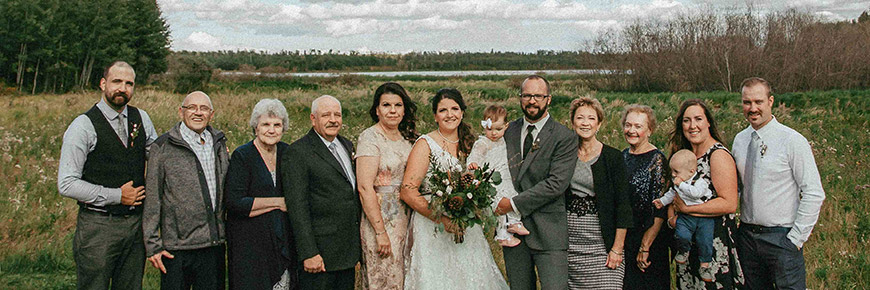 Les participants à un mariage comportant moins de 25 invités prennent des photos sur les rives du lac Astotin.