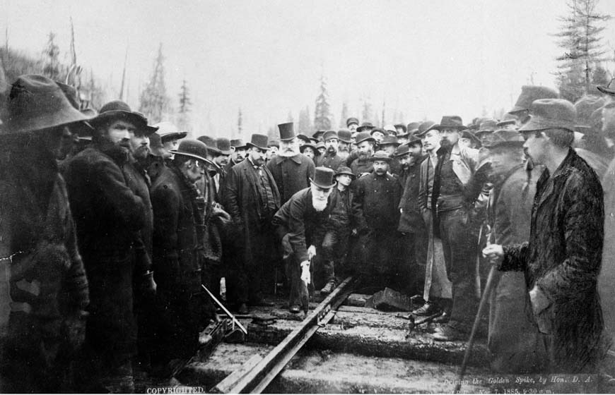 Photo célèbre de la pose du dernier crampon dans le chemin de fer transcanadien par un homme à la barbe blanche coiffé d’un haut-de-forme.