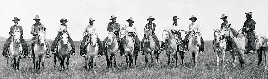 Onze cow‑boys à cheval, alignés côte à côte.