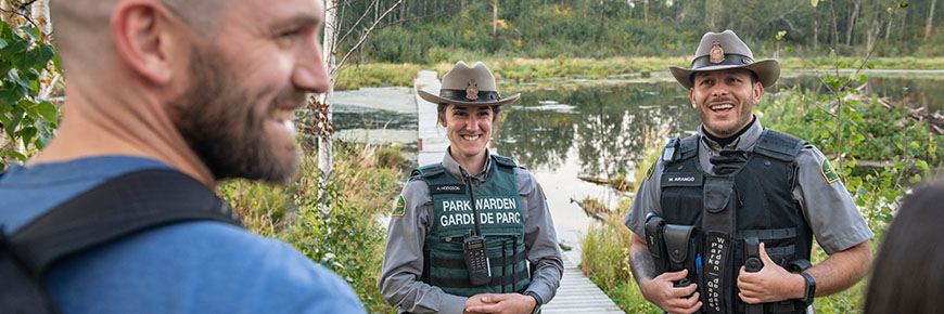 Deux gardes de Parcs Canada donnent de l’information sur la sécurité à des randonneurs.