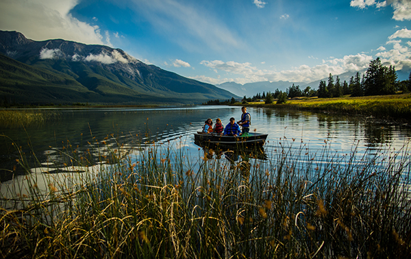 Group of people wearing life vests on a canoe in the middle of a lake.