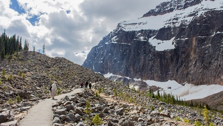 Group of people on a paved trail with rocky terrain on both sides. 
