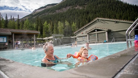 Adult and child play in an outdoor pool.