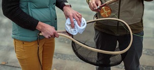 Close-up of a fish net being cleaned with a white cloth.
