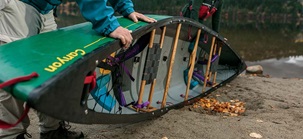 Close-up of a canoe lying on its side on the shore, being prepared for cleaning.
