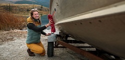 Adult kneeling and cleaning the side of a boat.