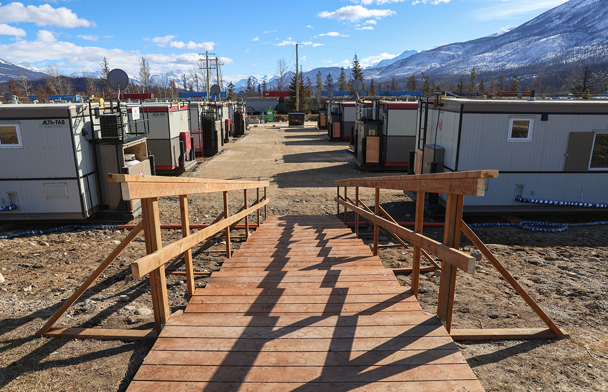 A wooden staircase leading to a section of land with interim housing units on both sides.
