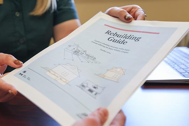 Close-up of a Parks Canada staff member handing over a rebuilding guide.