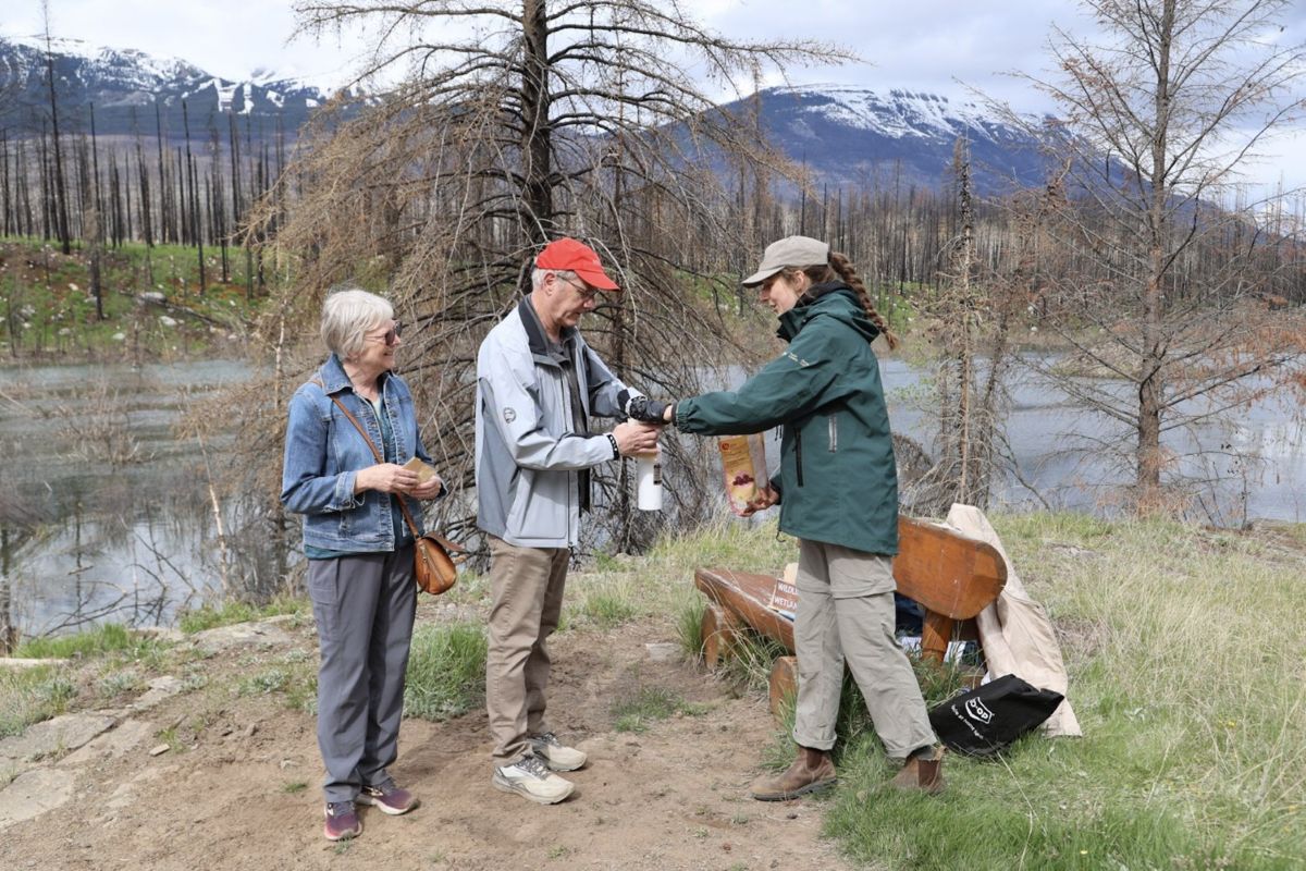 Des visiteurs reçoivent avec plaisir un ingrédient de mélange montagnard tout en échangeant sur la faune du milieu humide. Référence photographique : Merel Pilgrim, Parcs Canada.