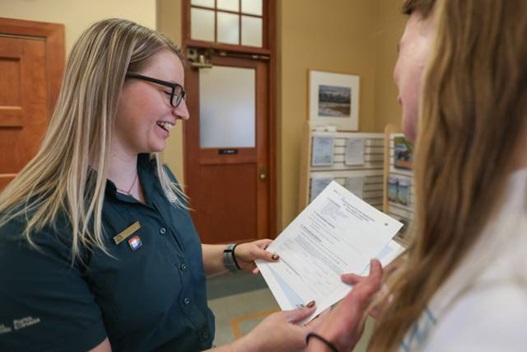 Parks Canada staff member shows paperwork to a resident who looks at it.