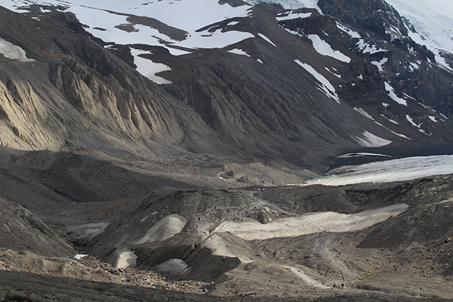 View of the forefield in summer, featuring gravelly and uneven terrain with some remaining patches of ice.