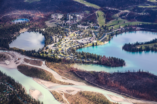 A bird's-eye view of the terrain, featuring several circular or oval lakes, some buildings, and a braided river.