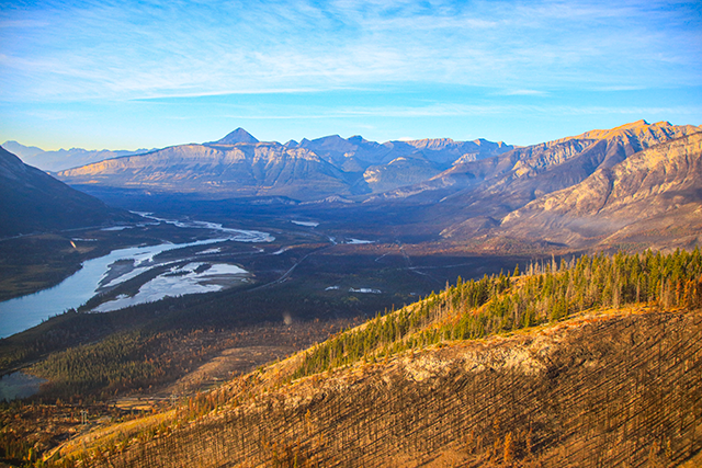 A sunny landscape showcasing a U-shaped valley with a river flowing through the center.