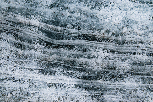 Close-up view of glacier ice showing its texture and horizontal lines.
