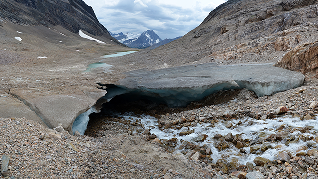 A glacier cave with rocky terrain and ice, revealing how ice lies beneath the surface of what initially appears to be rock.