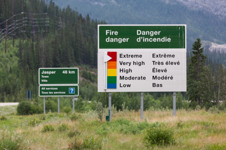 Deux panneaux de signalisation : l’un indique la distance jusqu’à Jasper, l’autre signale un risque d’incendie extrême avec une flèche.