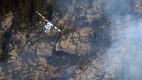 Aerial view of a helicopter dropping a water bucket.