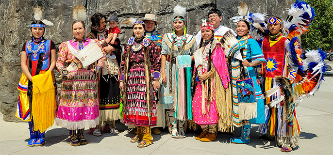 Un groupe de personnes vêtues d'habits traditionnels indigènes fait la queue pour une photo.