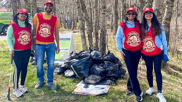 Four people with a pile of garbage bags
