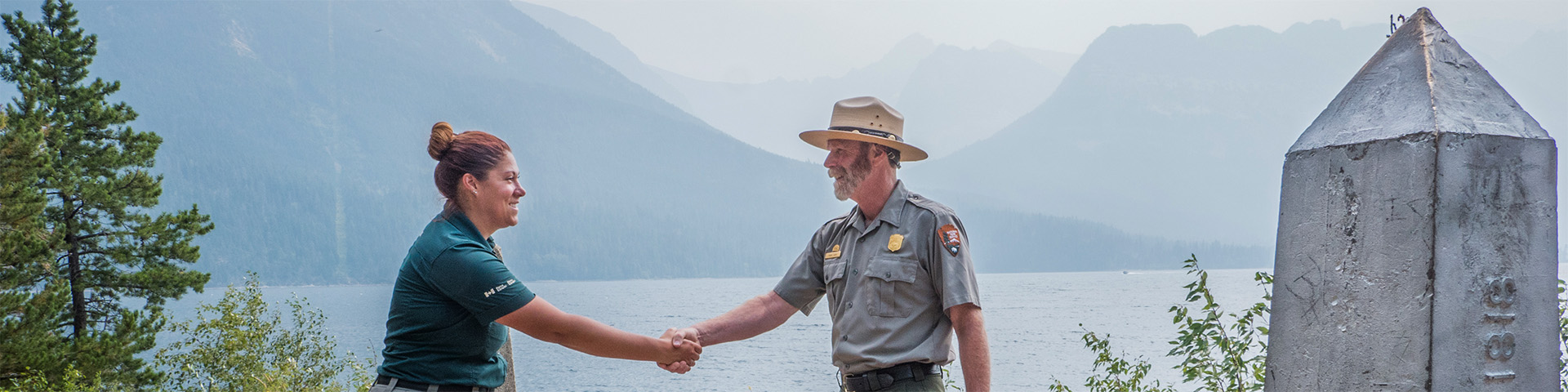 Un interprète de Parcs Canada et un garde du National Park Service des États-Unis se tenant côte à côte.