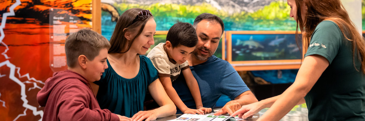 A family interacting with Parks Canada staff at the visitor centre