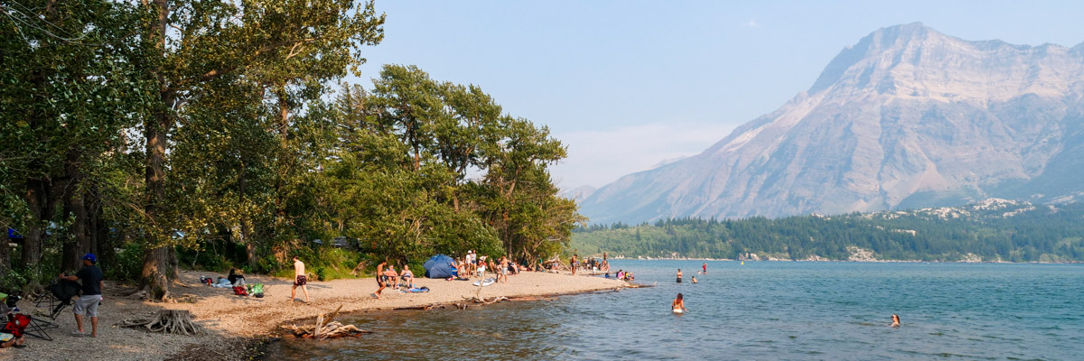 Visitors recreating at Emerald Bay with views of Upper Waterton Lake, the narrows and Vimy Peak in the background