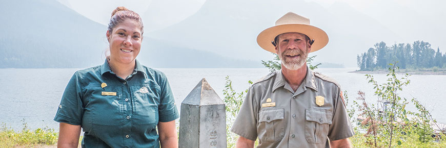 A Parks Canada interpreter and U.S. National Park Service ranger stand side by side