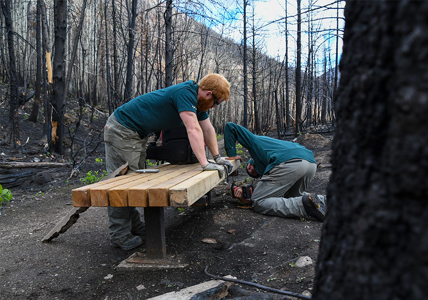 Trail crew build a new wooden bench on the trail