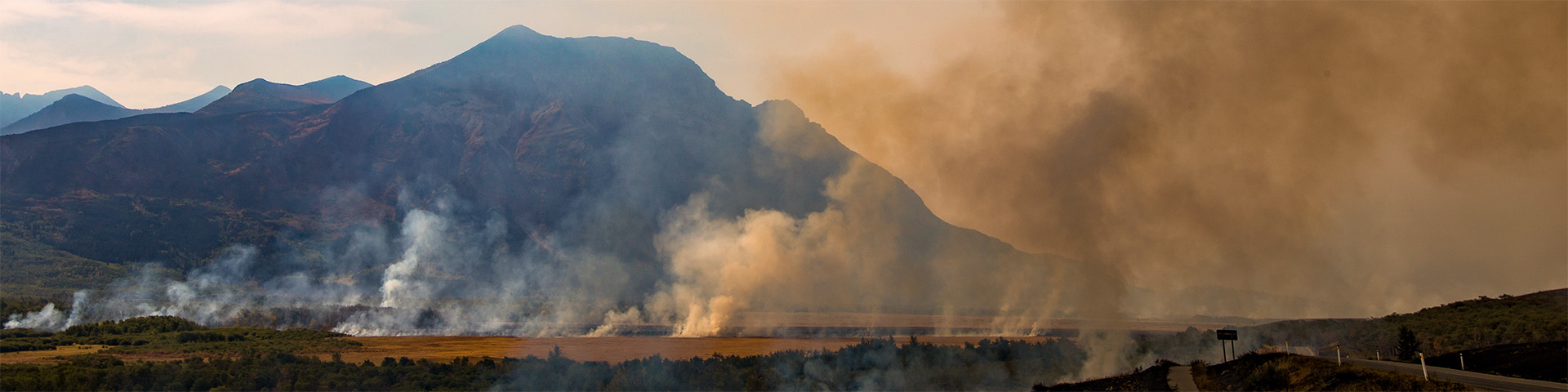 deux fauteuils rouges sur le bord d’un lac, une forêt en feu en arrière-plan