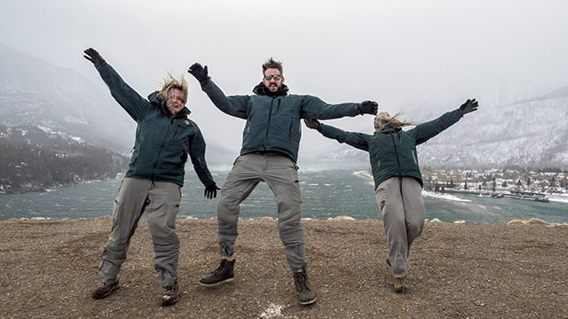 Three people pushing against a strong wind gust