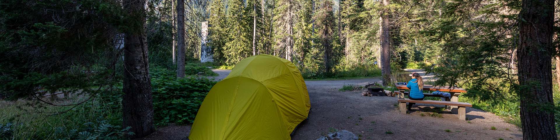 Une tente à côté d'une table de pique-nique dans un camping de l'avant-pays