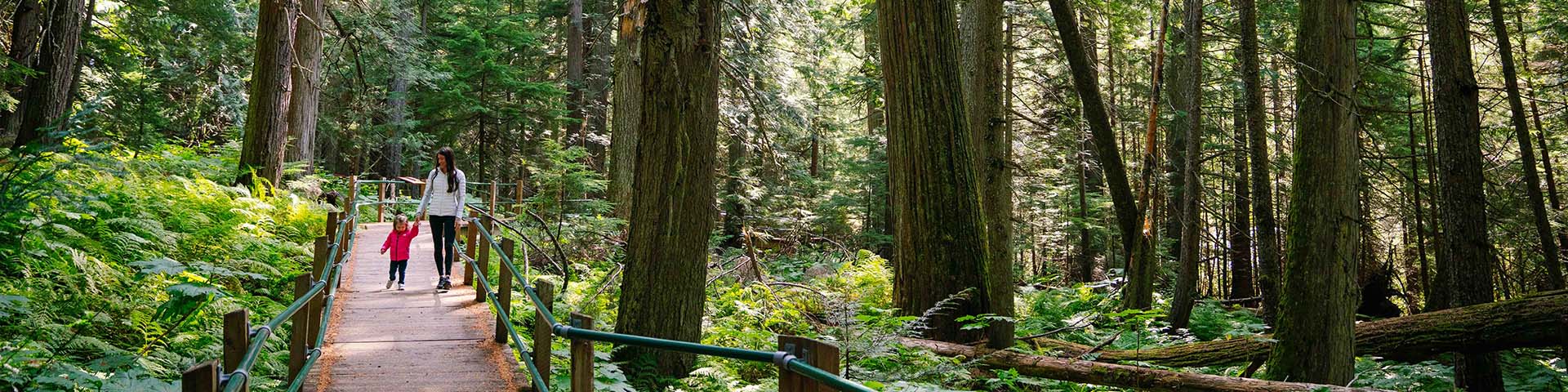 Mother and daughter walking on a boardwalk in the woods