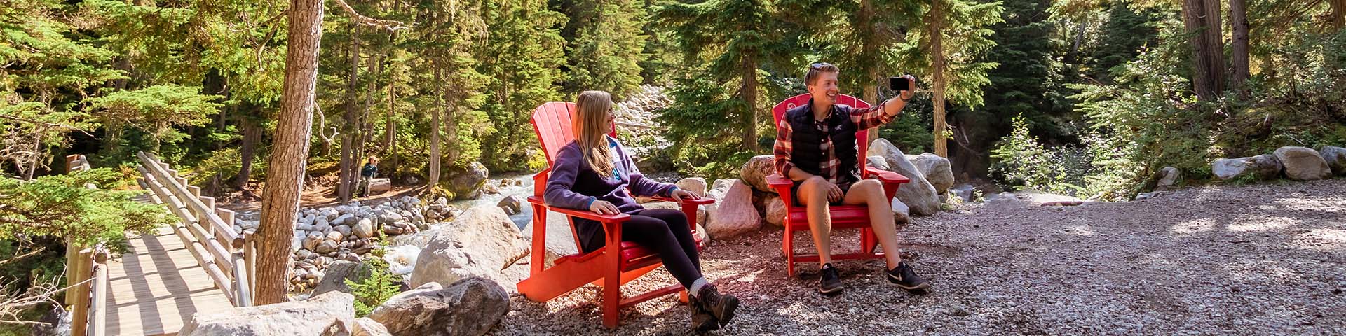 Two people relaxing in red adirondack chairs