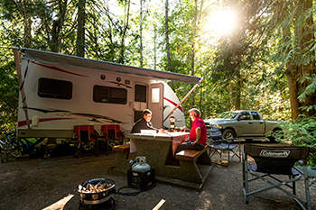 Un homme et une femme assis à une table de pique-nique dans un camping