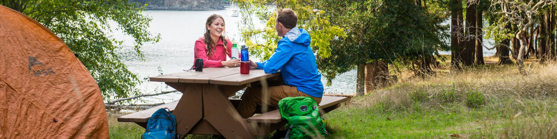 Un jeune couple assis à une table de pique-nique surplombant la baie de Narvaez, l'île de Saturna