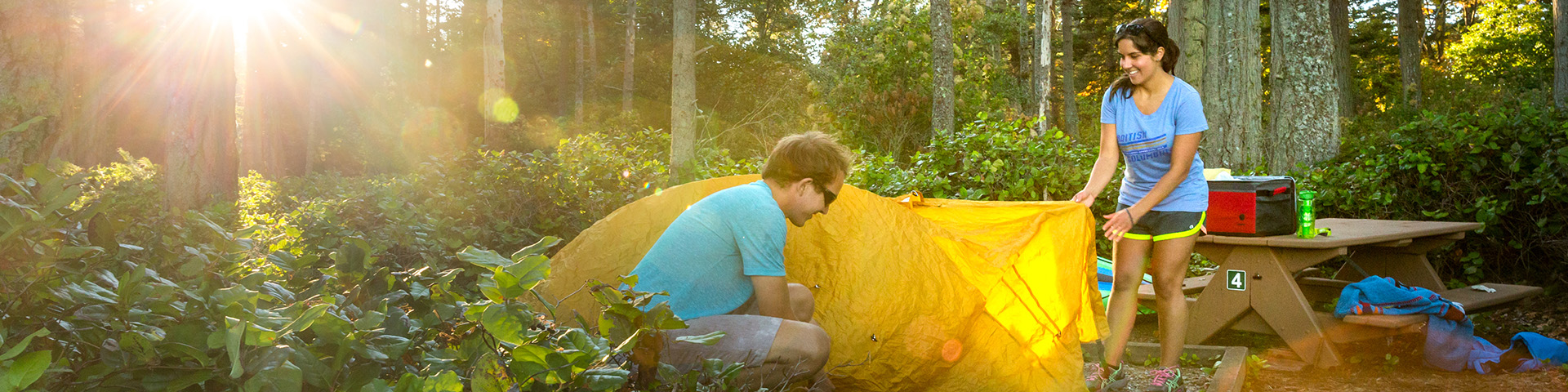 A young couple sets up their tent on their campsite on D'Arcy Island