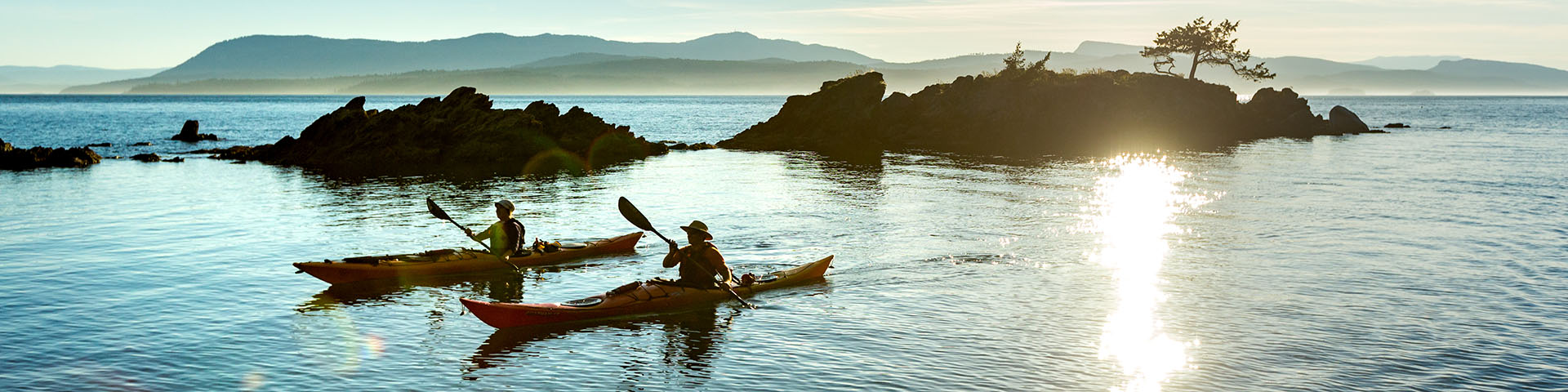 Par une soirée ensoleillée d'été, deux kayakistes s'approchent du camping isolé de la baie Shingle sur l'Île Pender.
